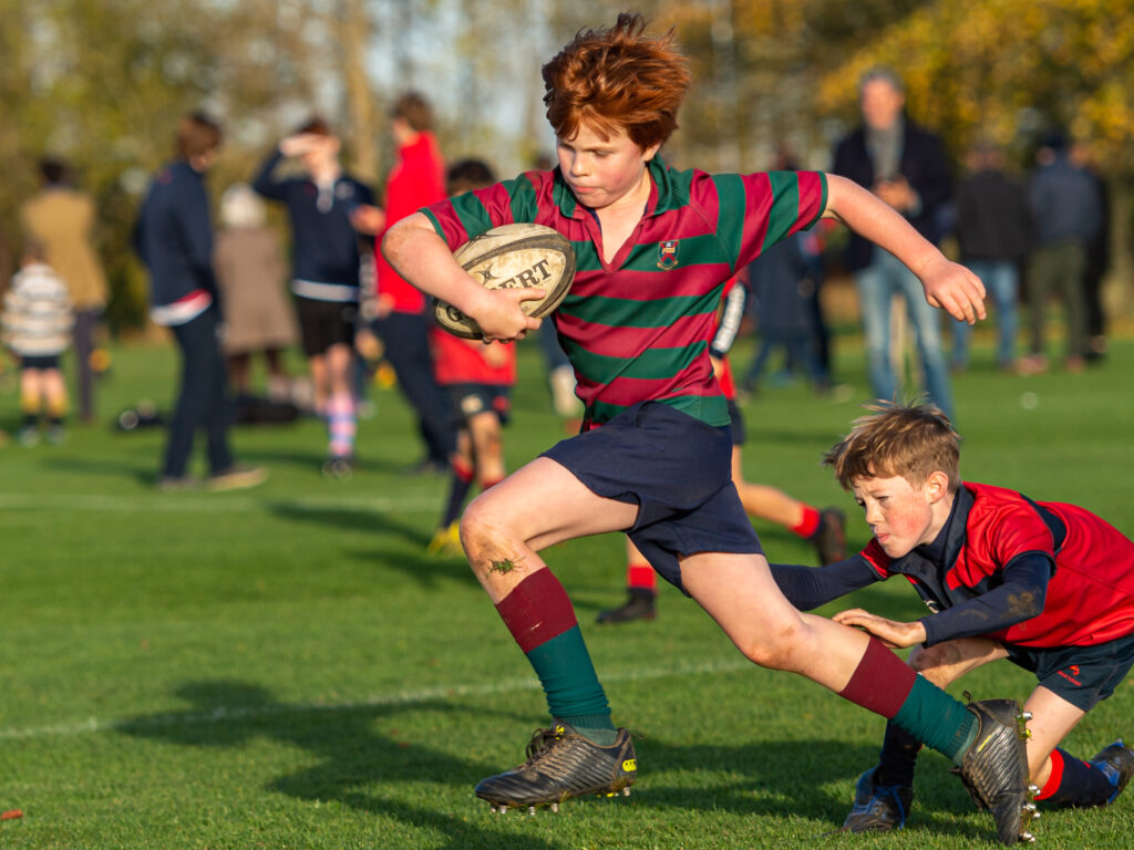 young boy running, playing rugby