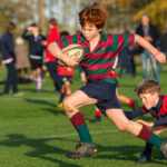 young boy running, playing rugby